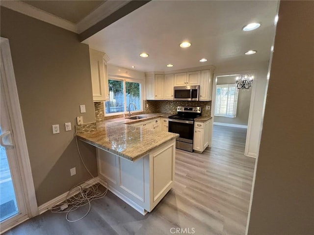 kitchen with appliances with stainless steel finishes, a sink, white cabinets, and plenty of natural light