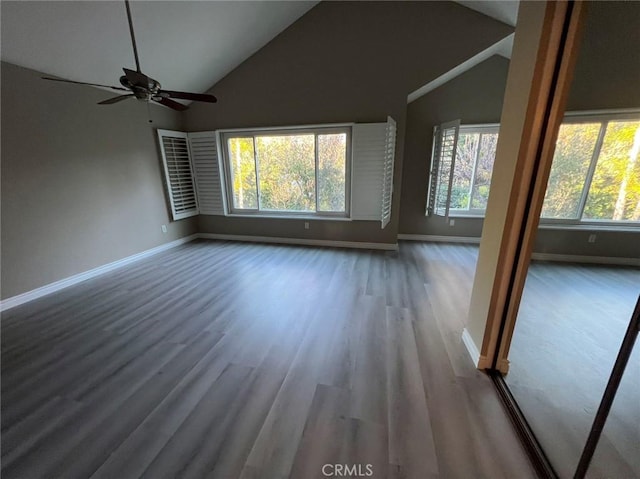 unfurnished living room with wood finished floors, ceiling fan, baseboards, and vaulted ceiling