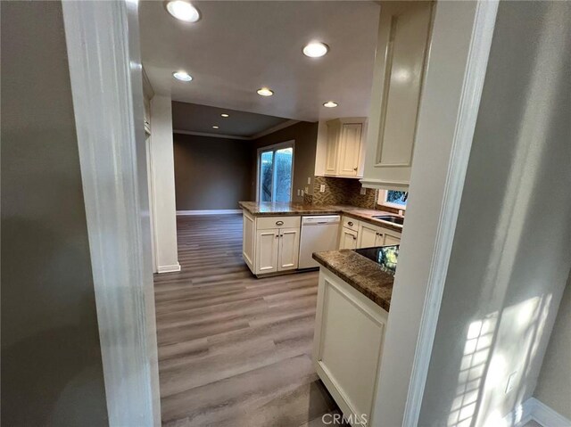 kitchen featuring white cabinets, light wood-type flooring, dishwasher, and baseboards