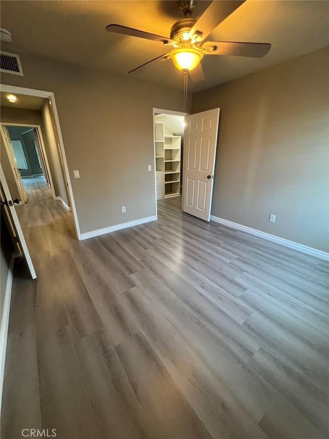 unfurnished bedroom featuring ceiling fan, visible vents, baseboards, and wood finished floors