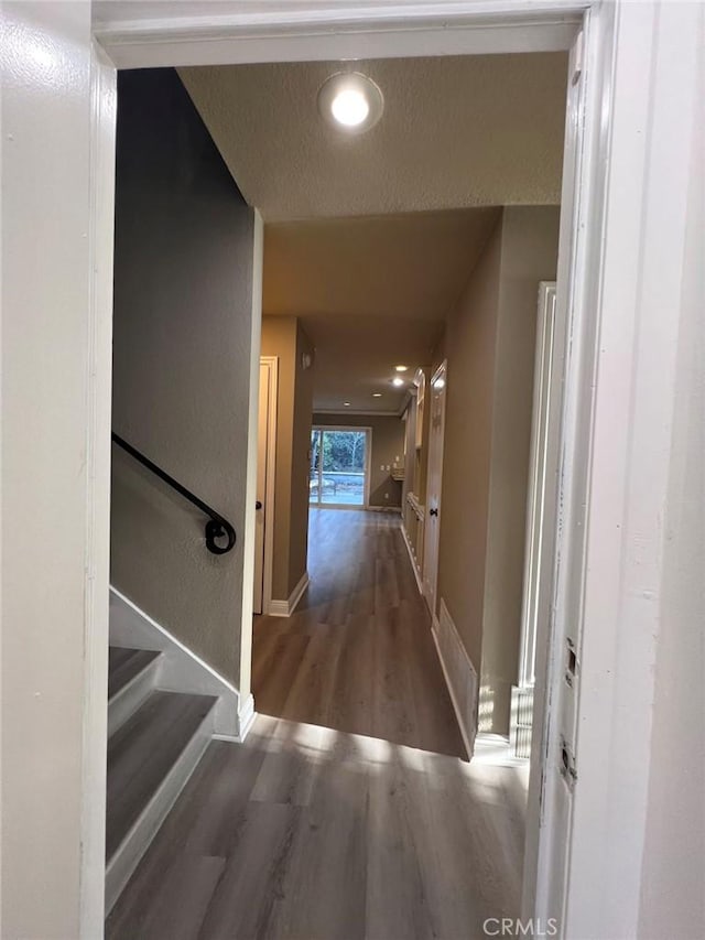 corridor with wood finished floors, recessed lighting, baseboards, and stairway