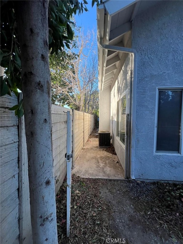view of property exterior featuring stucco siding, central AC, and fence