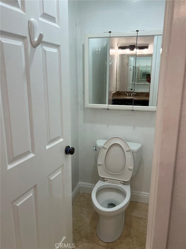 bathroom with toilet, baseboards, and tile patterned flooring