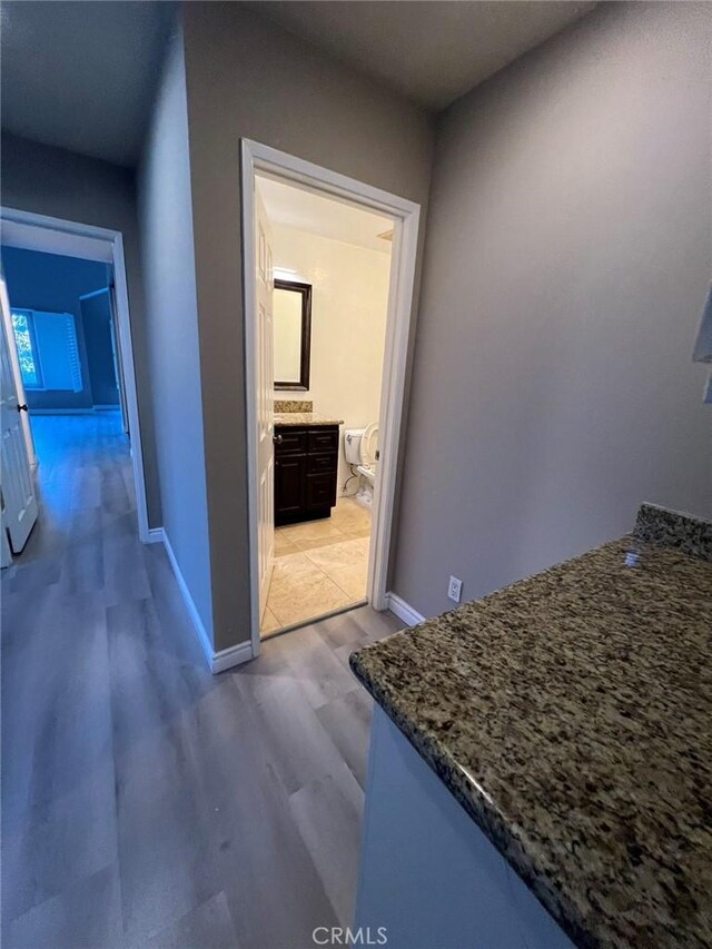 corridor with baseboards and light wood finished floors
