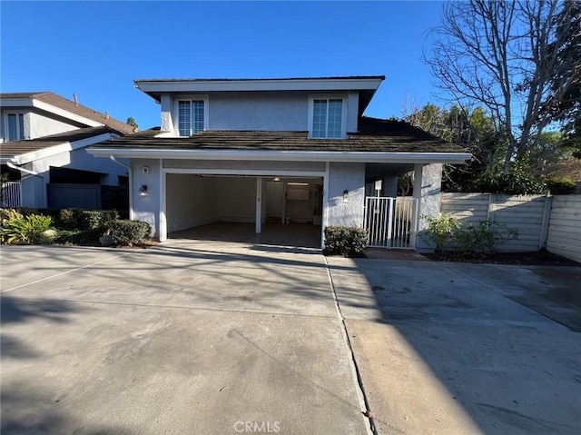 traditional home featuring concrete driveway, stucco siding, a gate, a garage, and fence