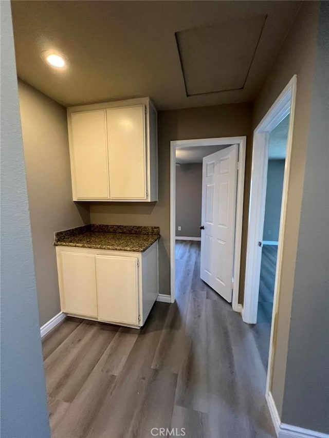hallway featuring baseboards, attic access, and dark wood-style floors
