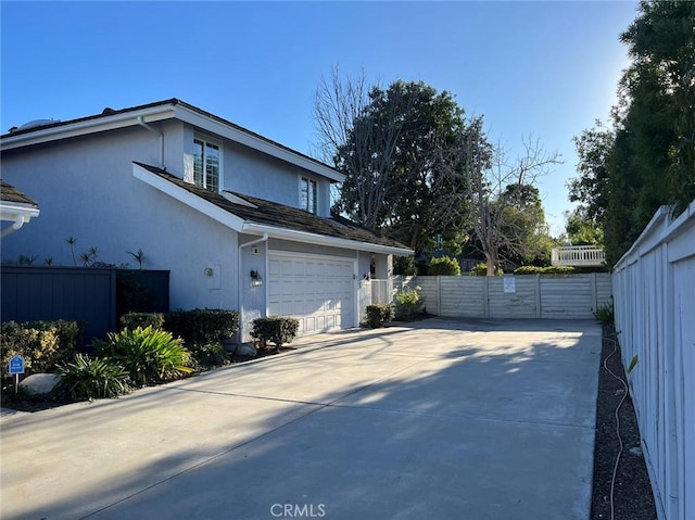 view of property exterior featuring concrete driveway, an attached garage, fence, and stucco siding