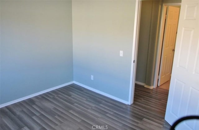 empty room with baseboards and dark wood finished floors