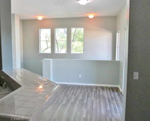 unfurnished dining area with wood finished floors and baseboards