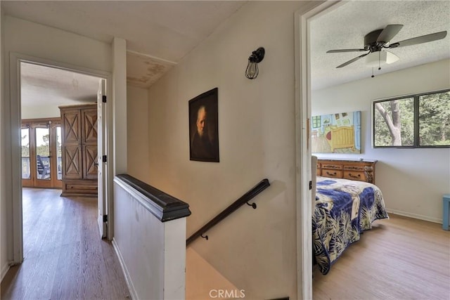 23677 Crest Forest Dr, Crestline, CA 92325 - hallway featuring wood finished floors, healthy amount of natural light, baseboards, an upstairs landing, and a textured ceiling