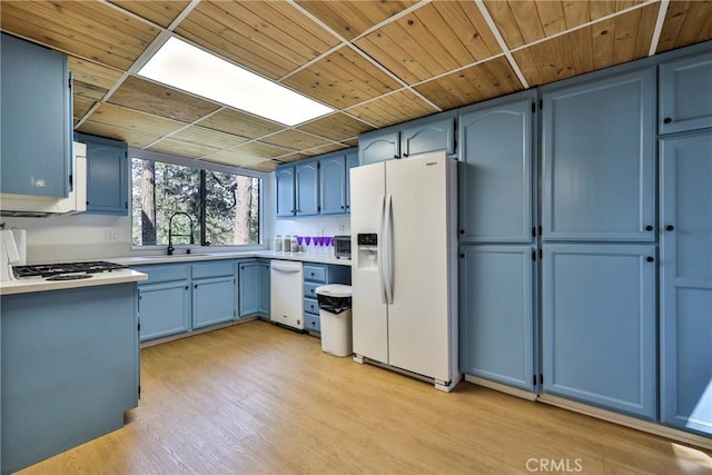 23677 Crest Forest Dr, Crestline, CA 92325 - kitchen with white appliances, blue cabinetry, a sink, light countertops, and light wood-style flooring