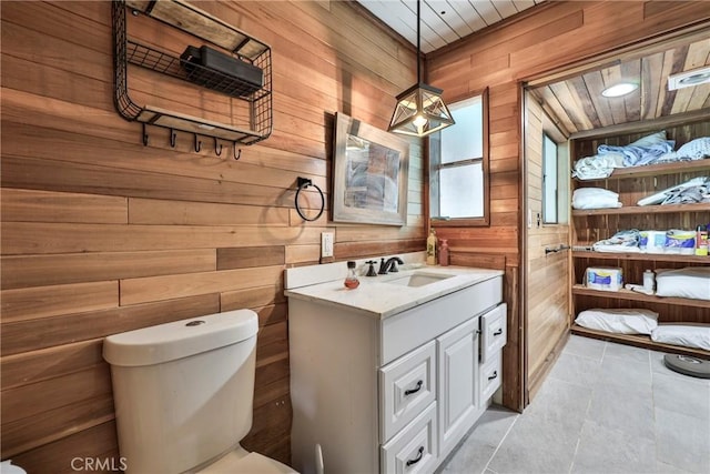 23677 Crest Forest Dr, Crestline, CA 92325 - bathroom featuring wooden walls, toilet, vanity, and tile patterned flooring
