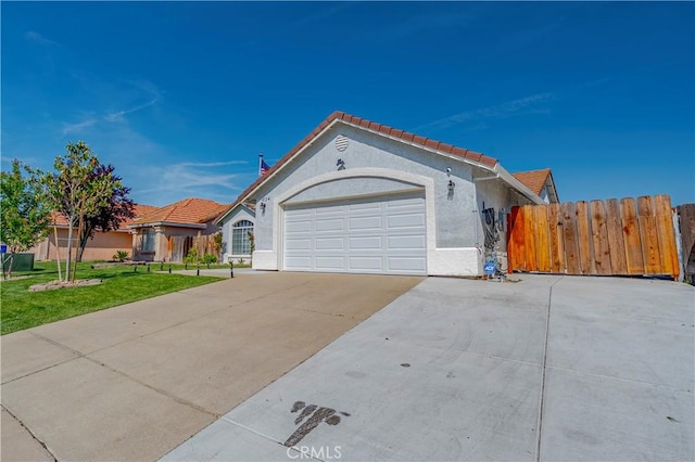 view of front of house with fence, a garage, stucco siding, a tiled roof, and driveway
