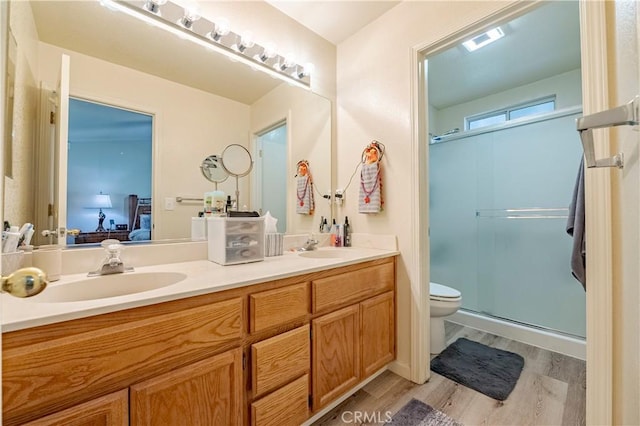 bathroom with wood finished floors, toilet, ensuite bathroom, a shower stall, and a sink
