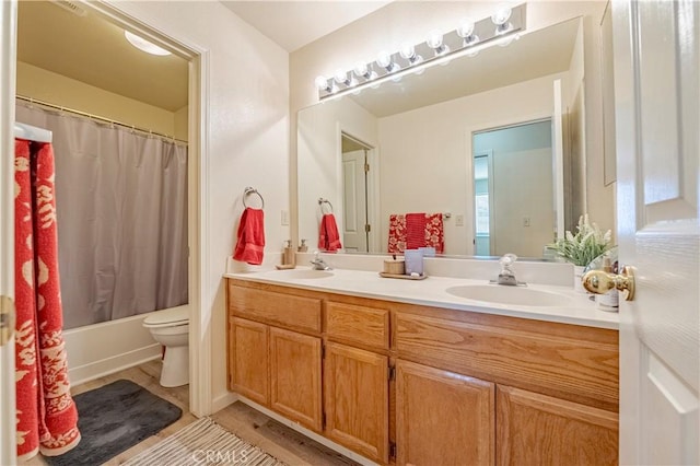 bathroom with double vanity, a sink, shower / bath combo, and toilet