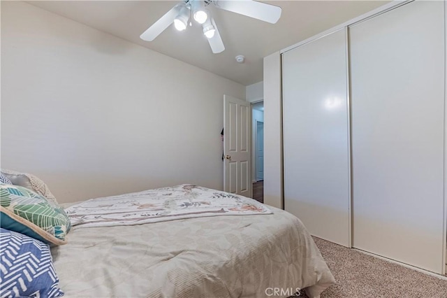 carpeted bedroom featuring ceiling fan and a closet