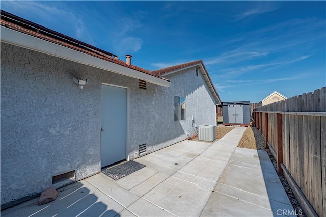 exterior space with a storage shed, a patio area, an outdoor structure, a fenced backyard, and stucco siding