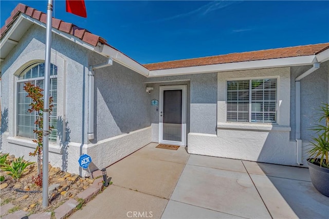 property entrance with a patio and stucco siding