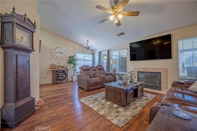 living area with visible vents, lofted ceiling, wood finished floors, ceiling fan, and a tiled fireplace