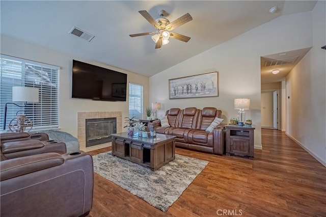 living area with visible vents, a ceiling fan, wood finished floors, and vaulted ceiling