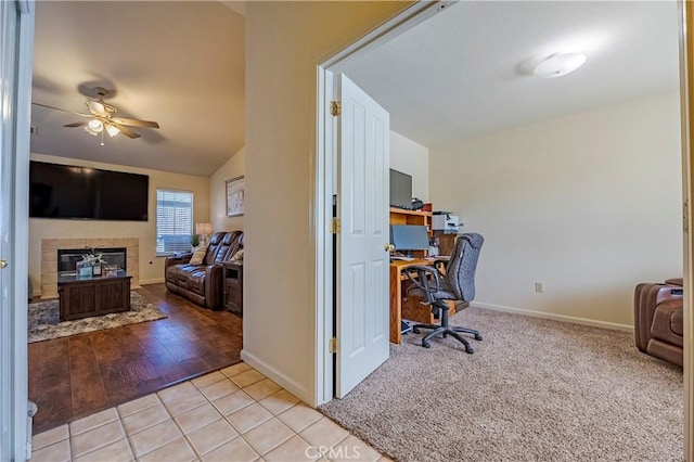 tiled office featuring a tiled fireplace, a ceiling fan, and baseboards