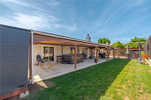 back of property featuring a hot tub, a fenced backyard, a chimney, a patio, and a yard