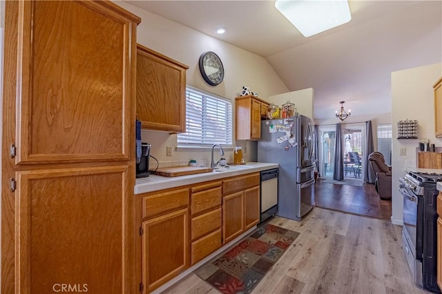 kitchen with stainless steel fridge, range with gas cooktop, a sink, light wood finished floors, and dishwasher