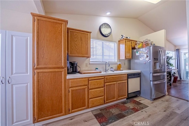 kitchen with stainless steel fridge, a sink, light wood-style flooring, dishwasher, and vaulted ceiling