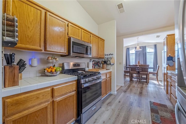 kitchen with visible vents, appliances with stainless steel finishes, vaulted ceiling, baseboards, and light wood-style flooring
