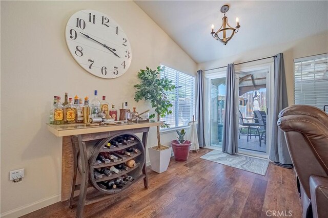 doorway with baseboards, a chandelier, wood finished floors, and lofted ceiling