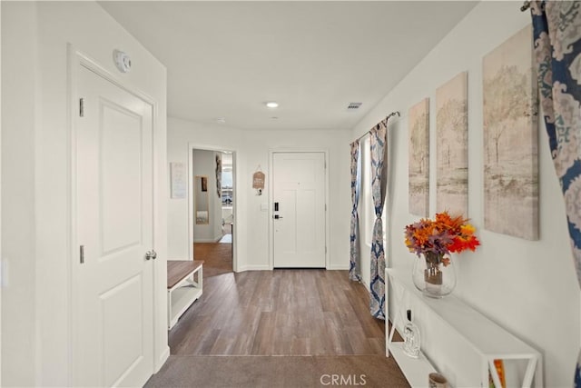 hallway featuring visible vents, baseboards, and wood finished floors