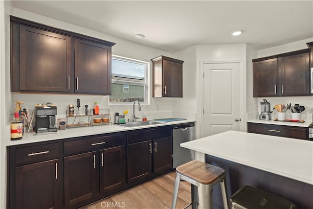 kitchen with stainless steel dishwasher, a breakfast bar area, light countertops, and a sink