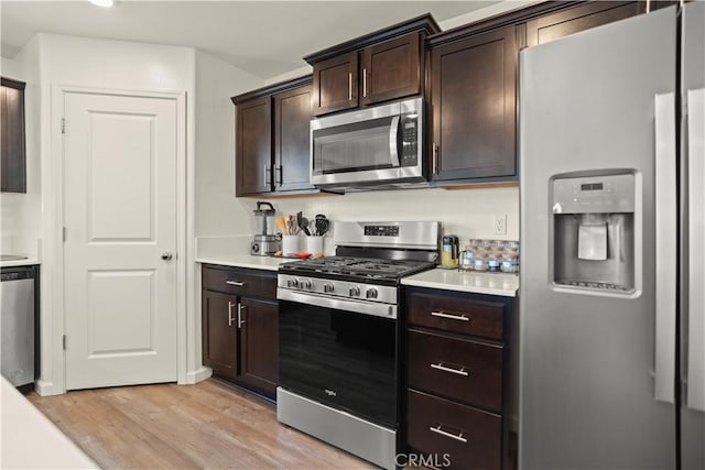 kitchen with light countertops, light wood-style floors, dark brown cabinets, and stainless steel appliances