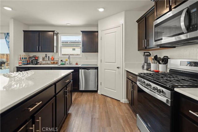 kitchen featuring a sink, light countertops, dark brown cabinetry, light wood-style floors, and stainless steel appliances