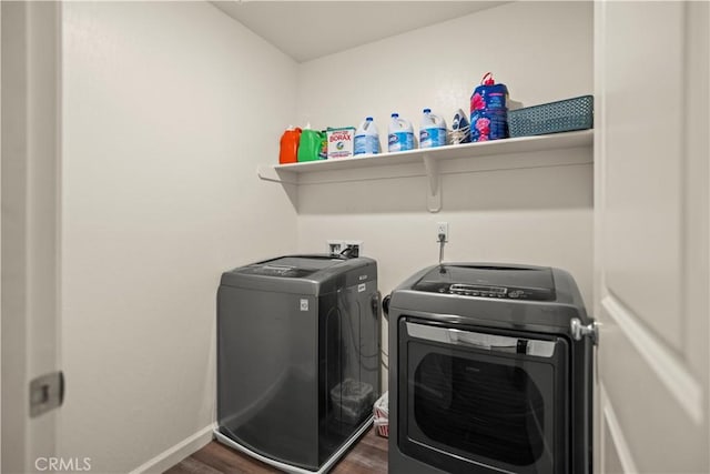 clothes washing area with washer and dryer, laundry area, baseboards, and dark wood finished floors