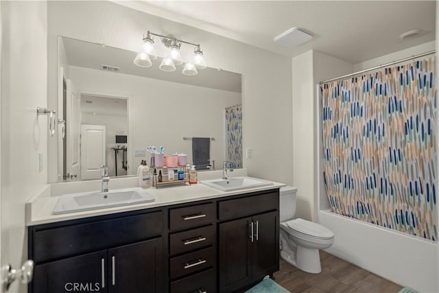 full bath featuring a sink, visible vents, double vanity, and wood finished floors