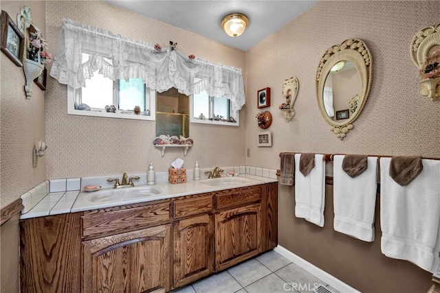 full bath featuring a shower with door, tile patterned floors, double vanity, and a sink