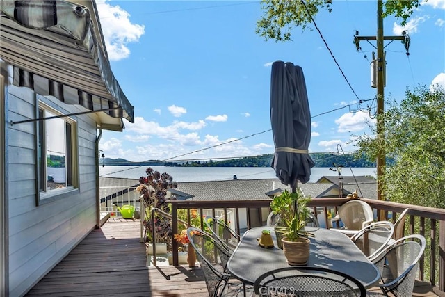deck with outdoor dining space and a water view