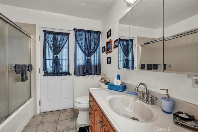bathroom with toilet, tile patterned flooring, shower / bath combination with glass door, and vanity