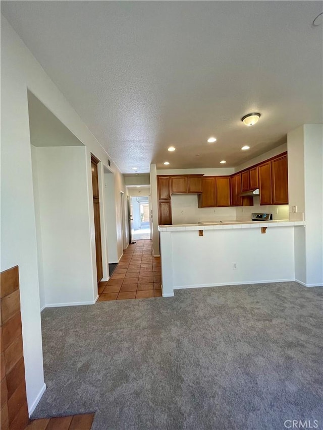 1800 E Lakeshore Dr Unit 302, Lake Elsinore, CA 92530 - kitchen featuring light countertops, carpet, a peninsula, under cabinet range hood, and recessed lighting