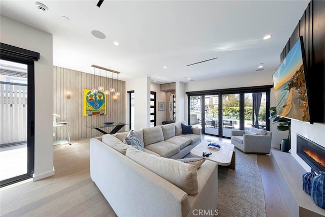 living room featuring a glass covered fireplace, light wood-style floors, and recessed lighting