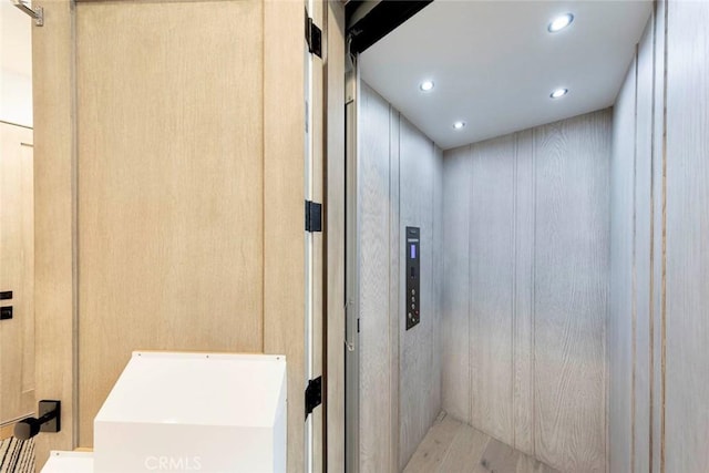 bathroom featuring wood finished floors, elevator, and recessed lighting