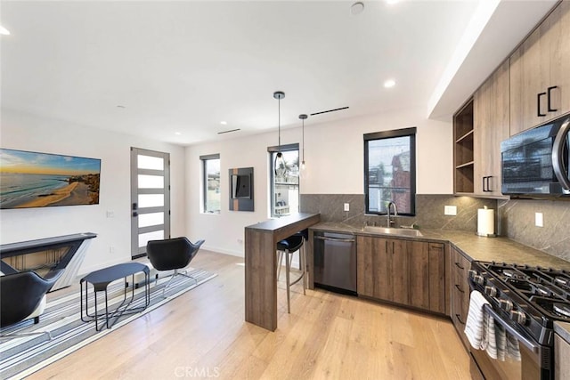 kitchen with stainless steel dishwasher, a sink, light wood-style flooring, black gas range oven, and recessed lighting