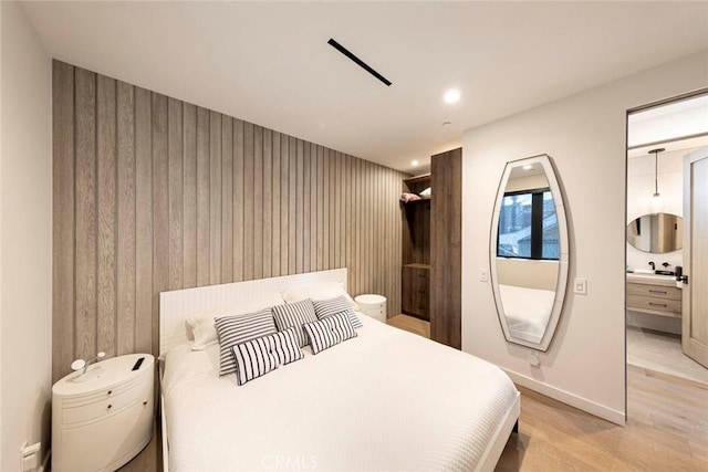 bedroom featuring light wood-type flooring, wooden walls, baseboards, and recessed lighting