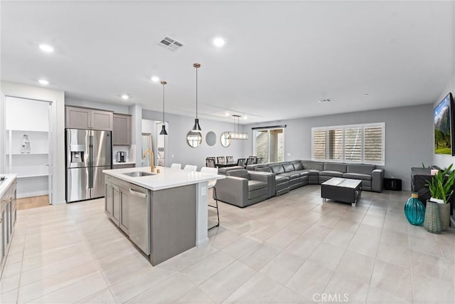 kitchen featuring stainless steel appliances, a sink, gray cabinets, plenty of natural light, and recessed lighting
