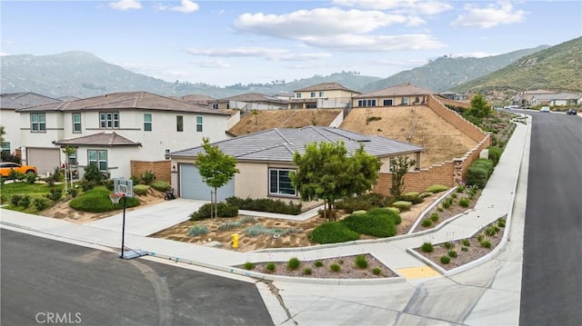 view of front of home with concrete driveway, a mountain view, a residential view, and a garage