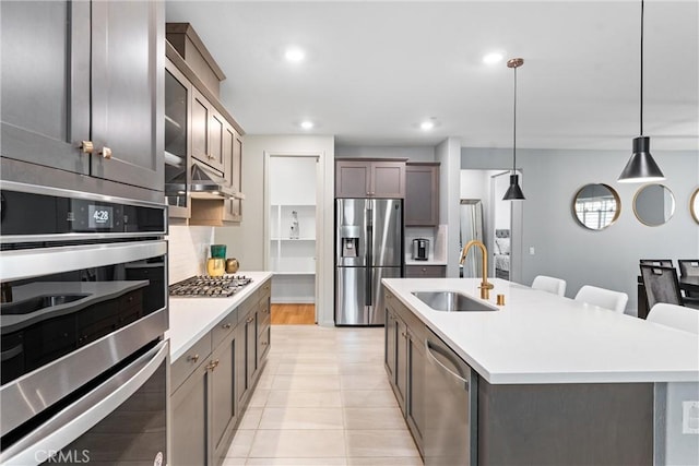kitchen with a sink, stainless steel appliances, light countertops, a kitchen island with sink, and recessed lighting
