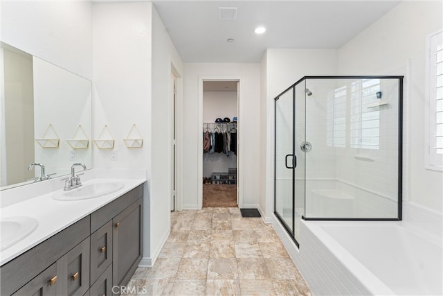 full bath with a stall shower, a spacious closet, double vanity, a tub to relax in, and recessed lighting