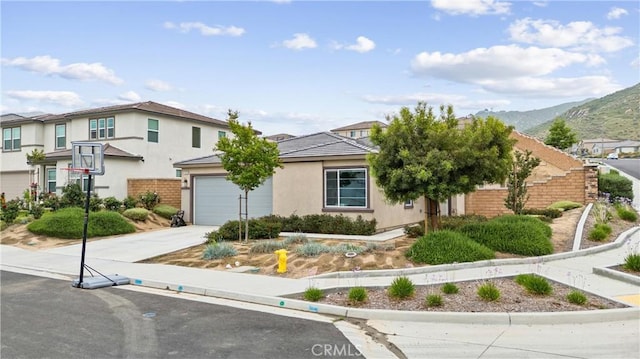 view of front facade with concrete driveway, stucco siding, a mountain view, and a garage