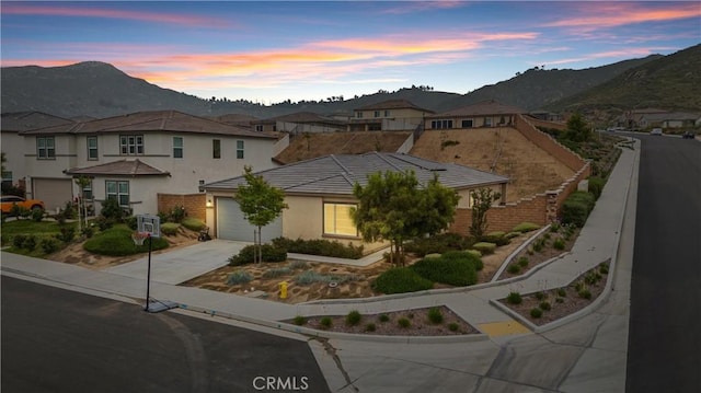 view of front of property with a mountain view, concrete driveway, an attached garage, stucco siding, and a residential view